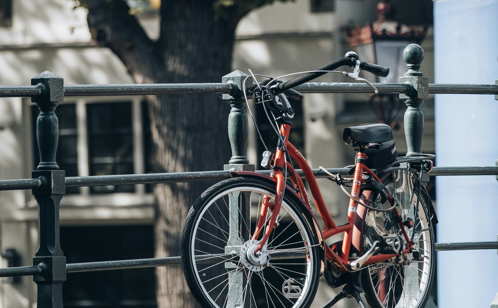 Bicicleta roja atada a una baranda en la calle
